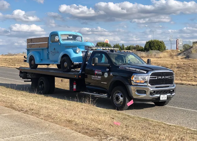 Vintage blue pickup secured on a flatbed tow truck